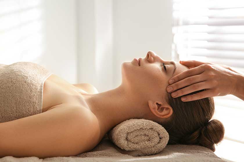 Young woman receiving head massage in spa salon